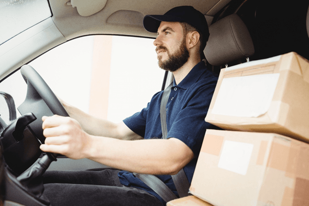 Man in a van with 3 brown boxes.