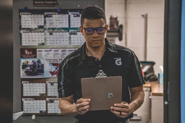 Mechanic holding a clipboard in front of an office.